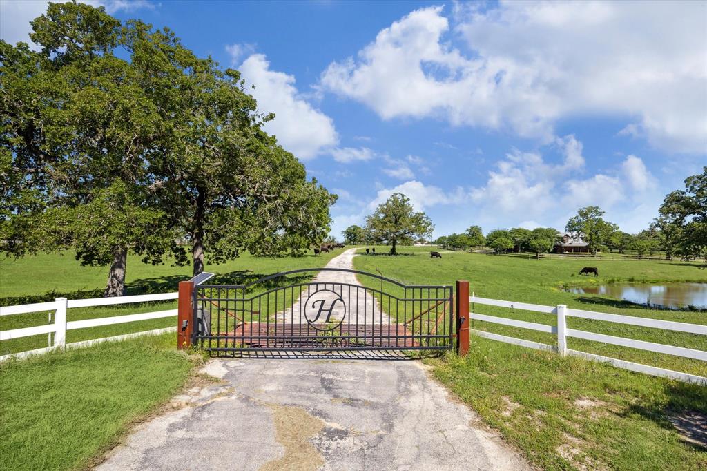 Welcome to Heaven Hill Ranch! Just off a winding country road, through the majestic, sculpted gate, paved paths will lead you around 68+ acres of undulating topography dotted with ancient oak trees and heavenly views. Seated at the crest of a rolling hill—just above a sky colored pond--lives a recent construction rustic-style log home with charm and all of today’s modern conveniences. The home features open concept Living with a soaring ceiling and stone fireplace plus hearth in the Great Room, a Chef’s Kitchen, full Mud Room with Powder Bath. First Floor Master has en-suite Bath+ Walk-in Closet. Second Floor features Loft Space with built-in Desk and bunk space, plus a Guest Suite with a full Bath. Continue down the path you will find a 3 car Garage, a spacious Barn, Corral, second Pond and trailer home that is being sold ‘As Is.’ Equidistant to College Station and Brenham this peaceful + private get away gives clearer meaning to the term God’s Country.
