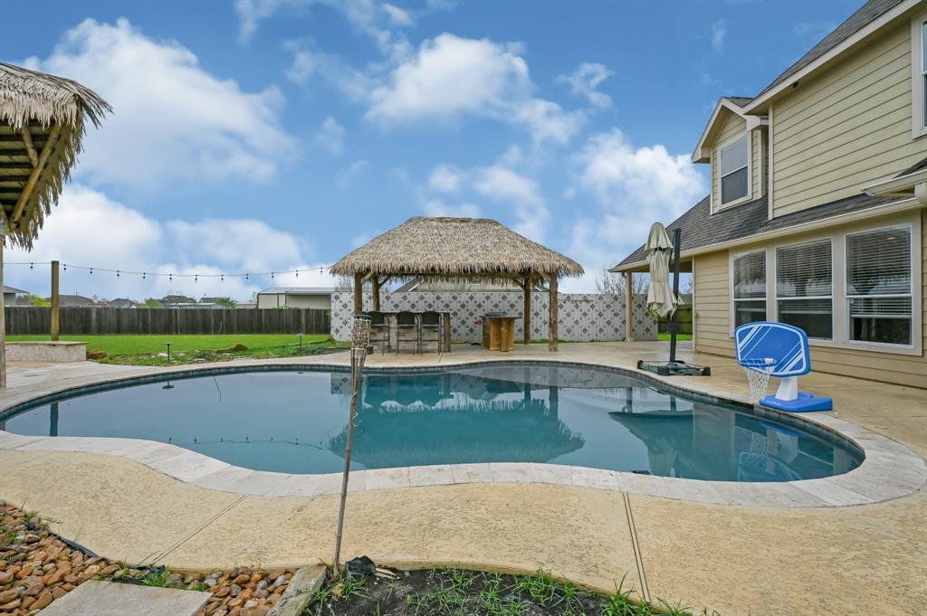 View of the outdoor kitchen featuring tv connections, outdoor fridge, bar seating, bbq pit.