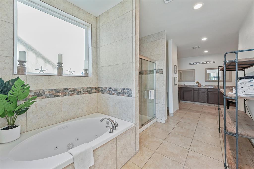 The spacious and elegant bathroom connected to the bedroom in the previous picture boasts both a walk-in shower and a jetted bathtub.