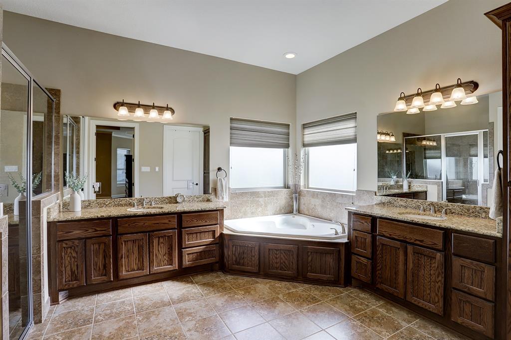 Large primary bathroom with distinct areas for the shower, garden tub, and separate sink areas that offer ample storage.