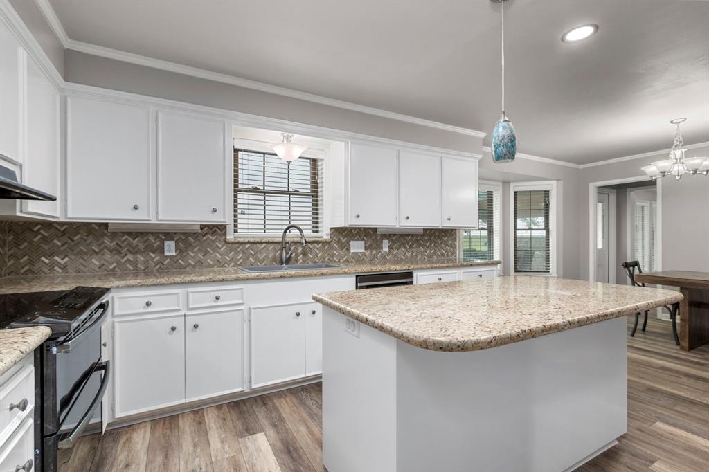 A closer view of the freshly painted cabinets, gleaming granite and beautiful tile backsplash. Island seating is perfect for those meals on the go.