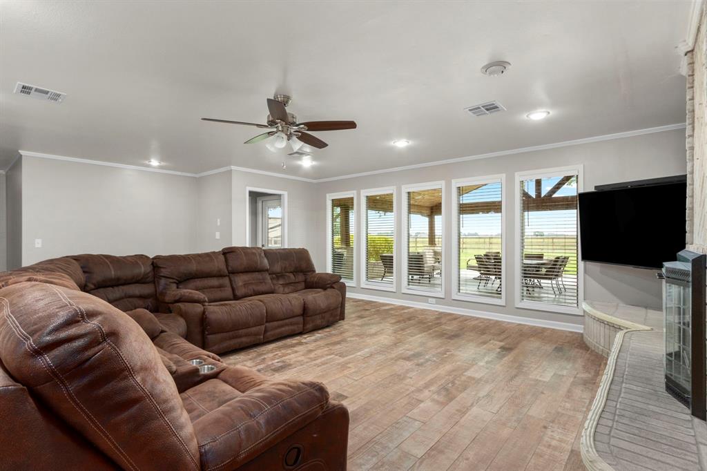 Floor to ceiling windows allow sunlight to stream in and provide picturesque views of the back acreage. The door leads to the expansive covered outdoor patio with full kitchen.