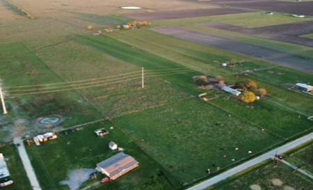 This is an older aerial photo showing no break in the grass.  Before the new lines were put up.   There are now NO utility poles located on this property.  Only over head utility lines.