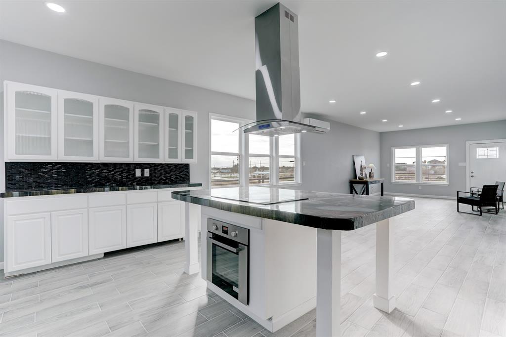 THE KITCHEN IS WITH HAND-POURED CONCRETE COUNTERS AND GLASS FRONT UPPER CABINETS.