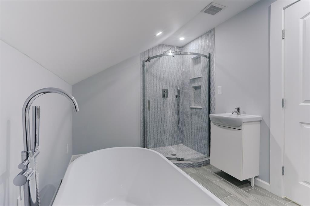 NICELY FINISHED PRIMARY BATH WITH STANDALONE TUB AND WALK-IN SHOWER WITH FLOOR TO CEILING GLASS TILE SURROUND.