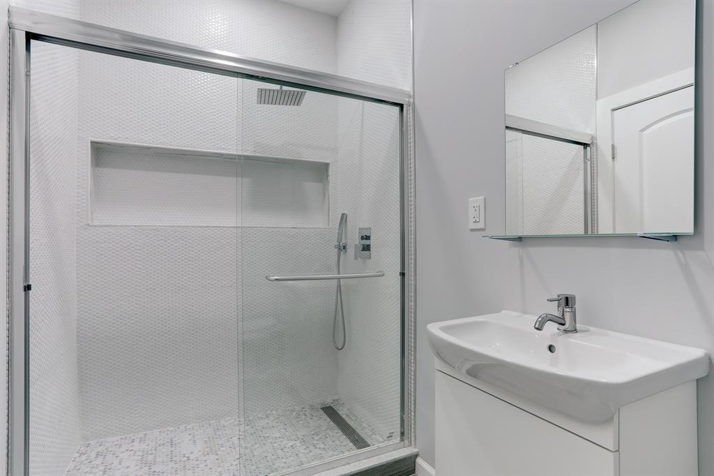 FULL BATHROOM WITH WALK-IN SHOWER AND TILED SURROUND.