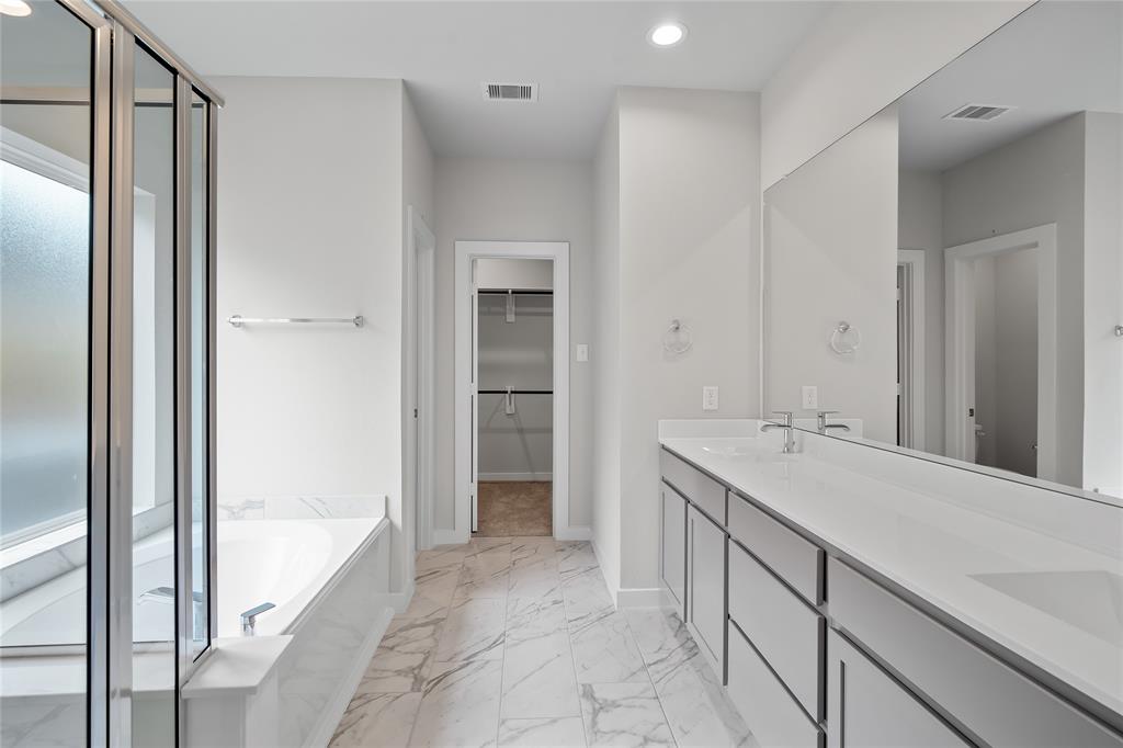 This primary bathroom is definitely move-in ready! Featuring white stained cabinets with light countertops, spacious walk-in closet with shelving, high ceilings, custom paint, sleek and dark modern finishes.