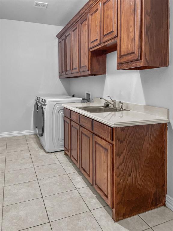 Laundry/Wash room with space for full-sized washer and dryer, sink, light tile flooring, and built-in cabinets