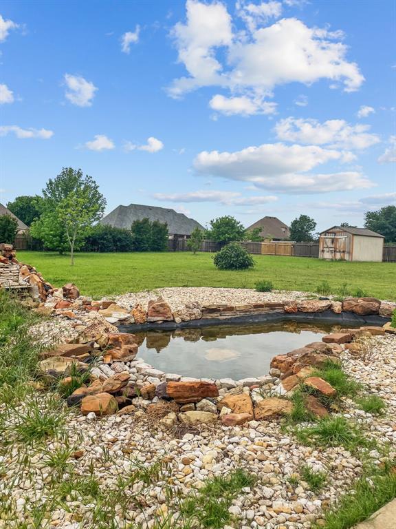 Unstocked pond with acreage view and a shed