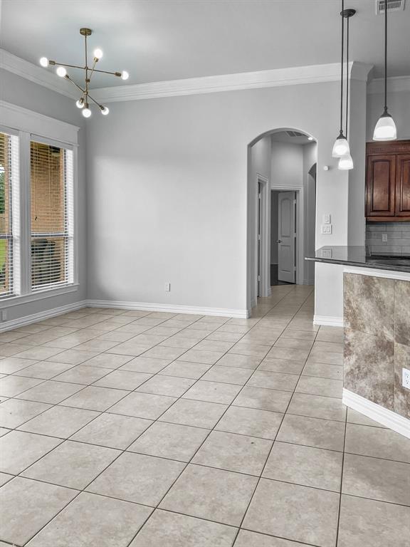 Tiled in-kitchen dining area featuring ornamental molding and modern light fixture