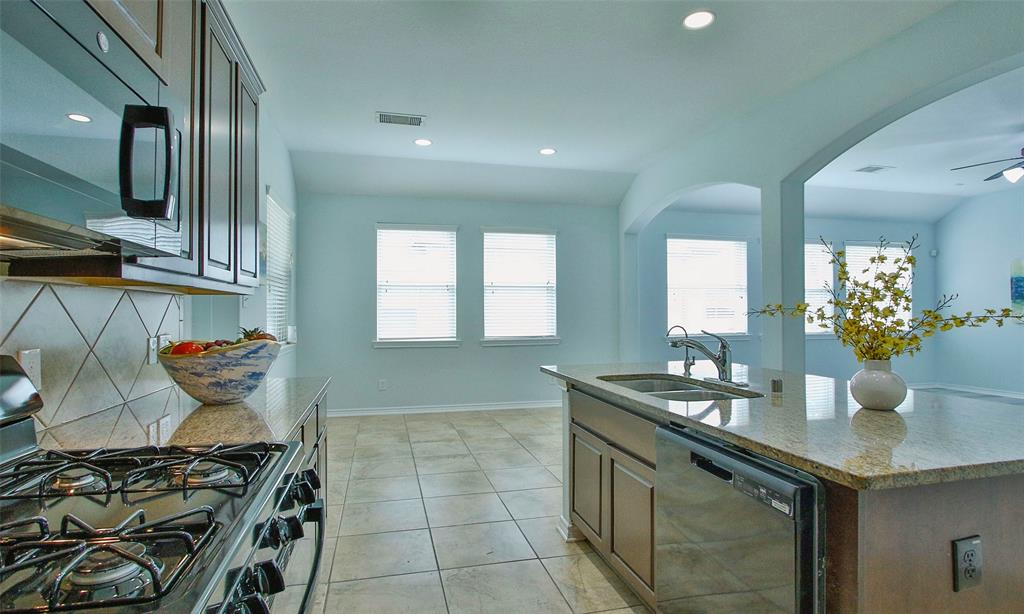 View of island kitchen with breakfast bar granite counter tops and lots of cabinets for storage.