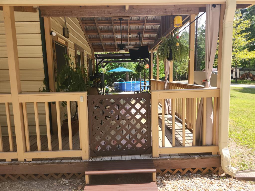 Great outdoor front porch space has it all! Tables, chairs, TV, ceiling fans, shelving and shade curtains for afternoon shade or privacy!