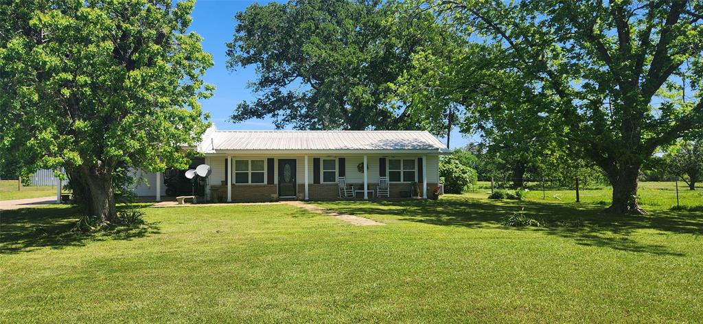 Acreage in Lovelady ISD with a 3 bedroom/1 bath house. The 29.5+ acres are fenced and have a 50X38 barn with water & electricity, a pond, pasture, and clusters of trees. There are pecan trees, pear trees, and a fig tree. The oversized 2-car carport has attic space above, a workroom including a workbench & shelves, and a half-bath.  The covered patio has a wood-burning fireplace. The exterior is low-maintenance vinyl siding with a metal roof. The house has been remodeled and updated over the years.  The updates include new windows, electrical, flooring, interior paint, bath, countertops & some cabinets, appliances, light fixtures, plumbing fixtures, tankless water heater, aerobic system, patio construction, carport, workroom, and concrete driveway.