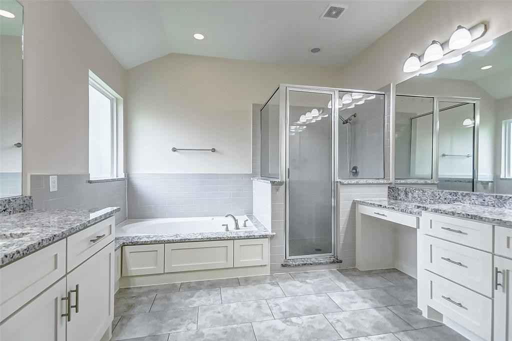 Primary bathroom featuring dual sinks with a vanity, shower and two person tub