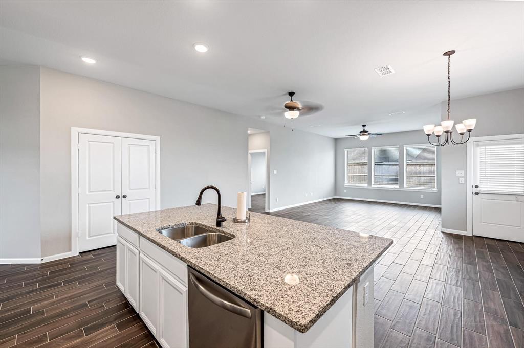 The large island kitchen sink faces out to both the living room and dining room, providing a seamless flow for entertaining and offering backyard views. Double doors on the left offer extra storage.