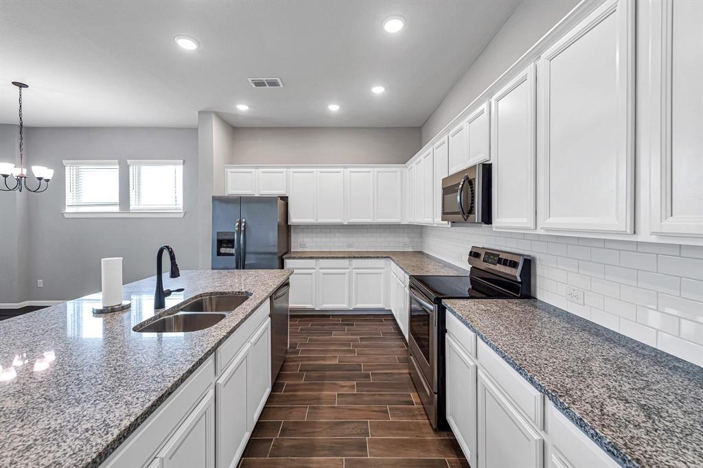 The home features recessed lighting, granite countertops, painted white cabinets, and a white subway tile backsplash, adding to its modern and stylish appeal.