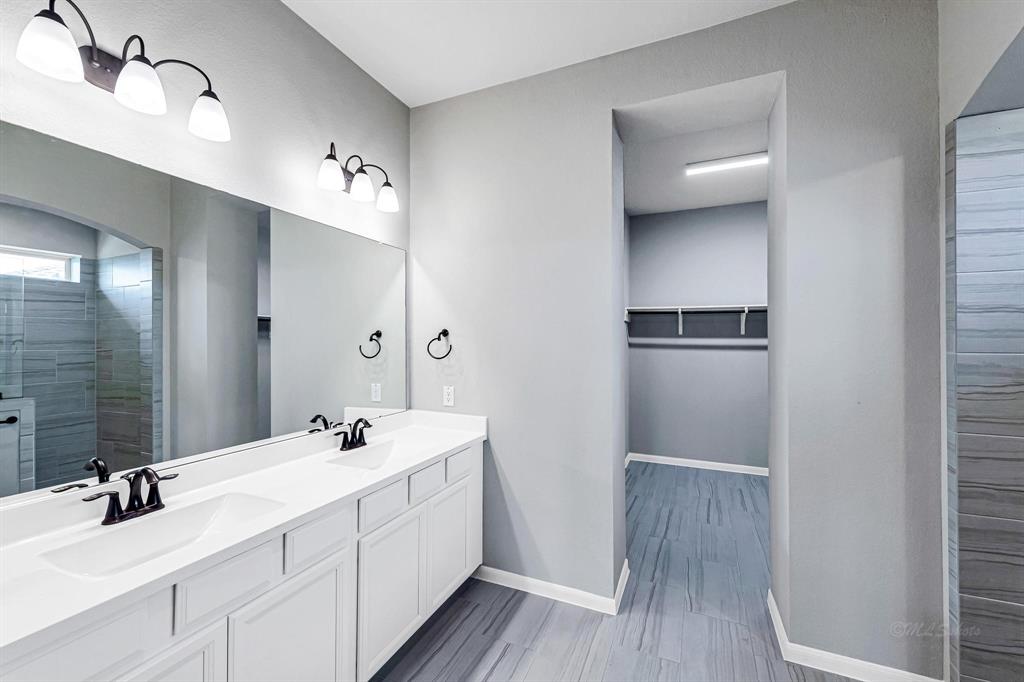 The ensuite offers a large bathroom with double sinks and a spacious vanity for storage. Additionally, it features a huge walk-in glass and tile shower, adding to the luxurious feel of the space.