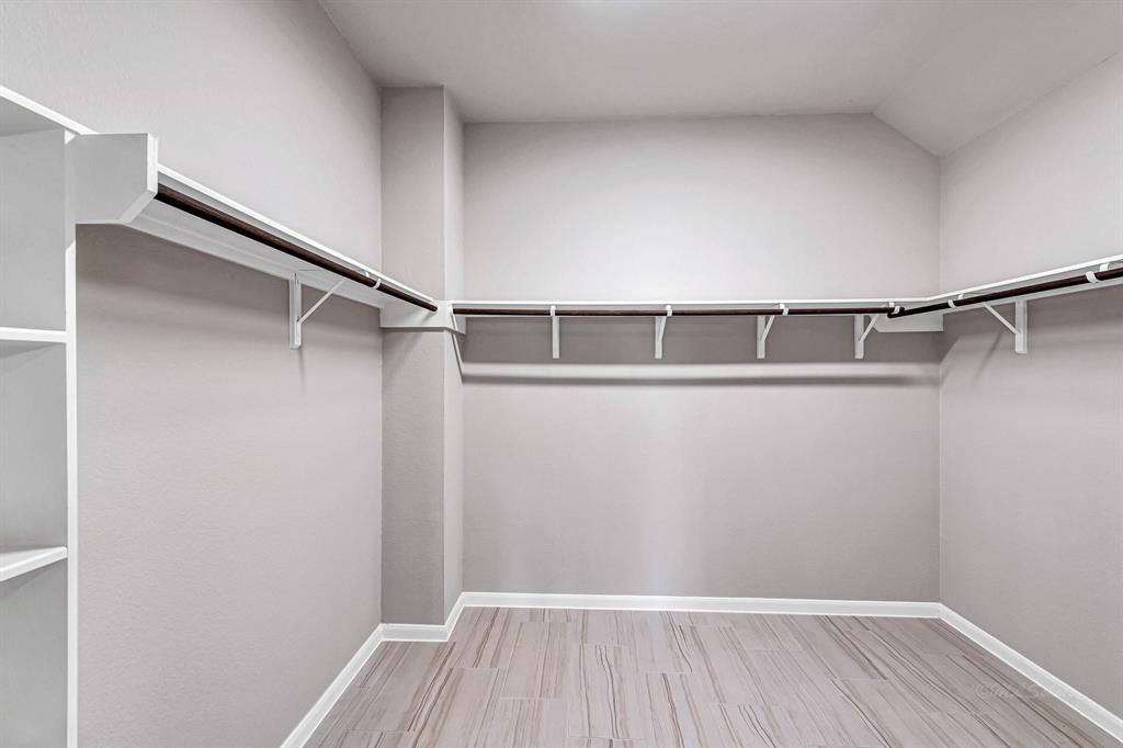 The massive walk-in wardrobe closet is complete with hanging rods throughout, offering ample space for organizing and storing your belongings.