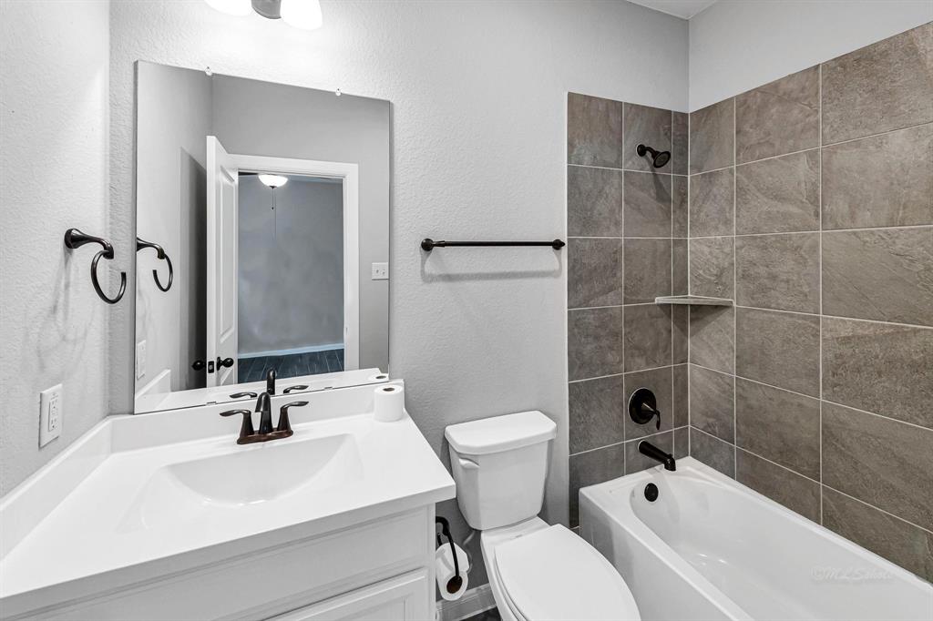 The home offers 3 full bathrooms. This particular bathroom is conveniently located near the guest rooms and features a shower-tub combo, adding practicality and convenience for guests.