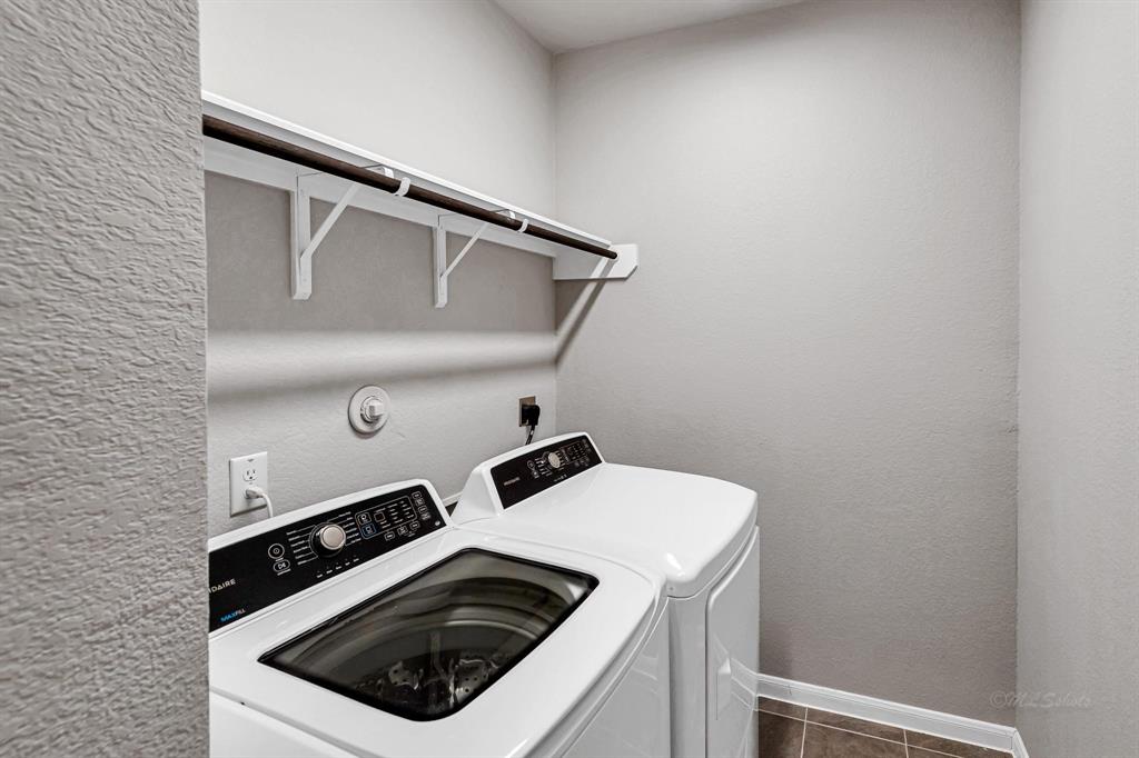 The utility room is equipped with hanging rods and shelves, providing practical storage solutions for keeping your laundry and other essentials organized.