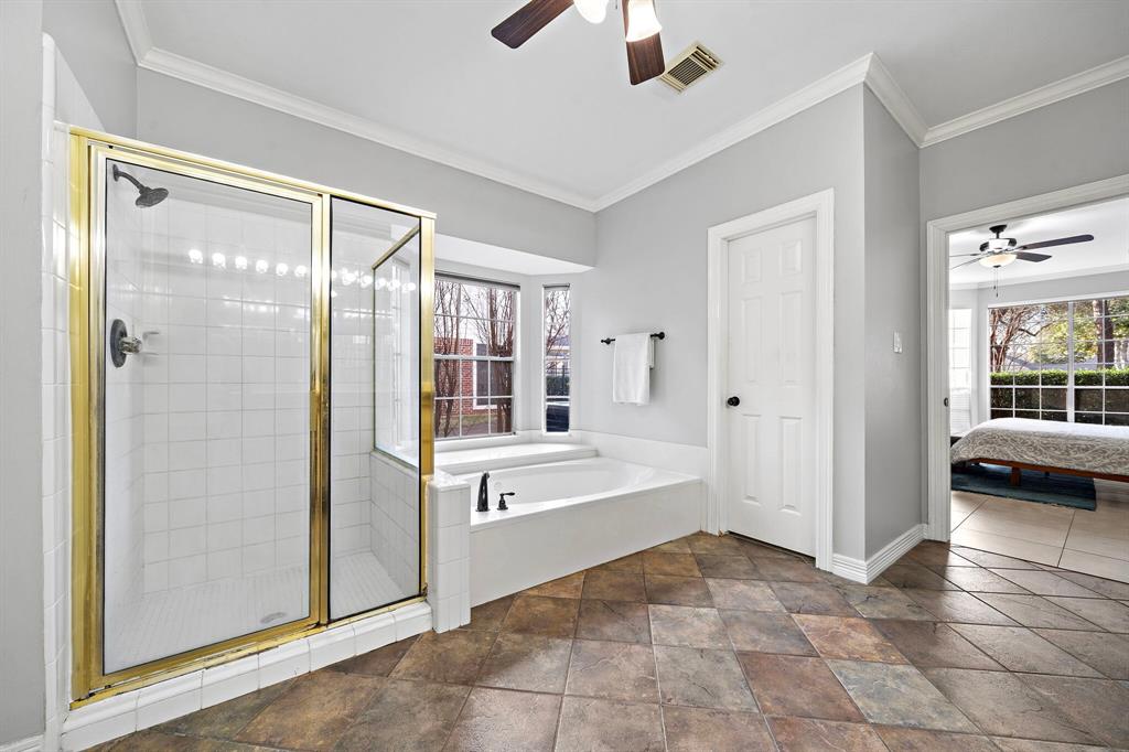 A spa-like retreat awaits in this primary ensuite bath with a glass-enclosed shower with tile surround, a jetted tub, a dual sink vanity, and a large walk-in closet.