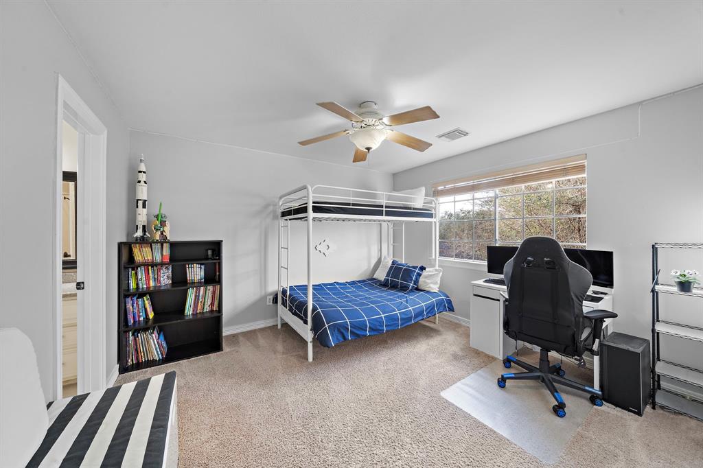 Easily convertible into a guest suite, this secondary bedroom features plush carpeting, a convenient Hollywood bath, and large windows showering the space with natural light.