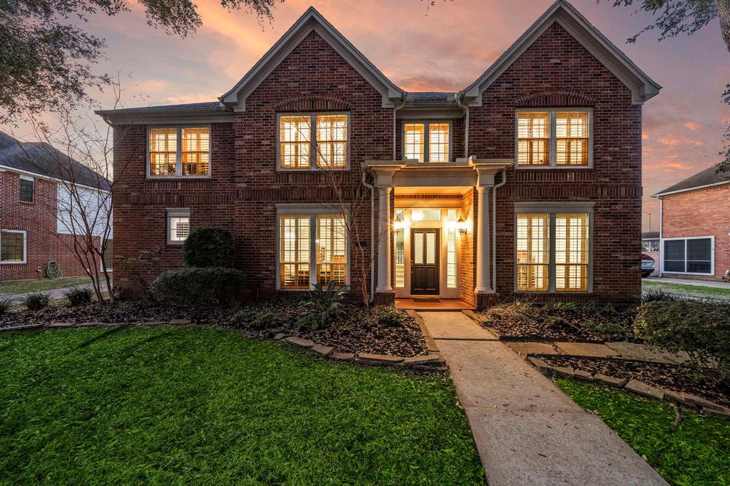 Situated on an expansive 9749 sq ft lot, this two-story home boasts impressive curb appeal with a lush front yard, ornate columns, and timeless brick exteriors.