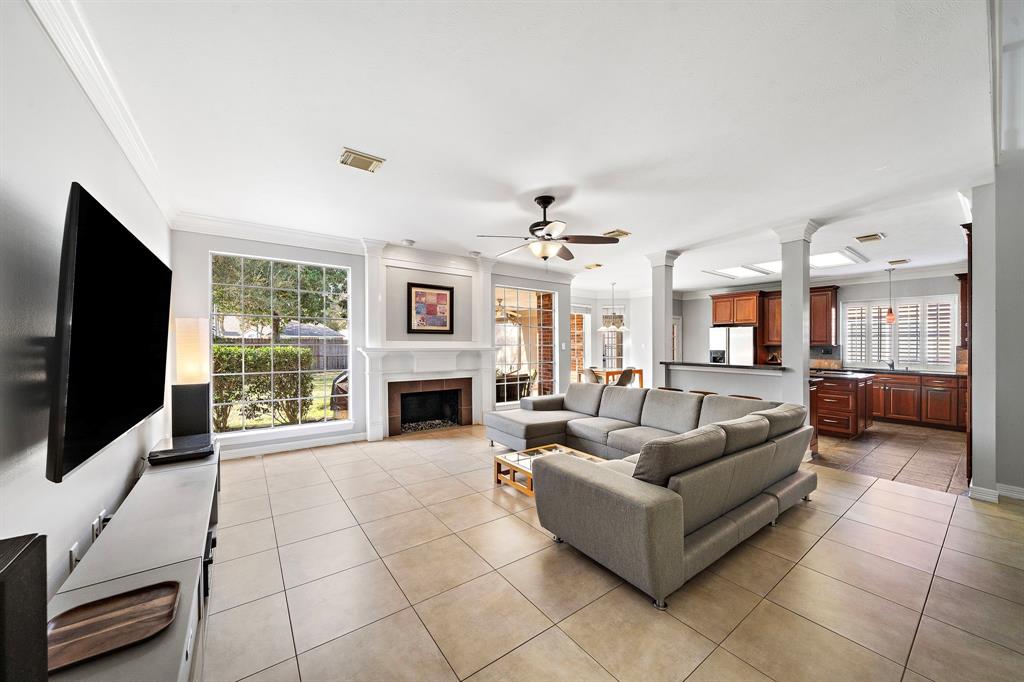 Step into an open and airy living space boasting high ceilings, a wood-burning fireplace, and tiled floors throughout. Expansive picture windows provide the room with natural light and captivating views of the verdant oasis.