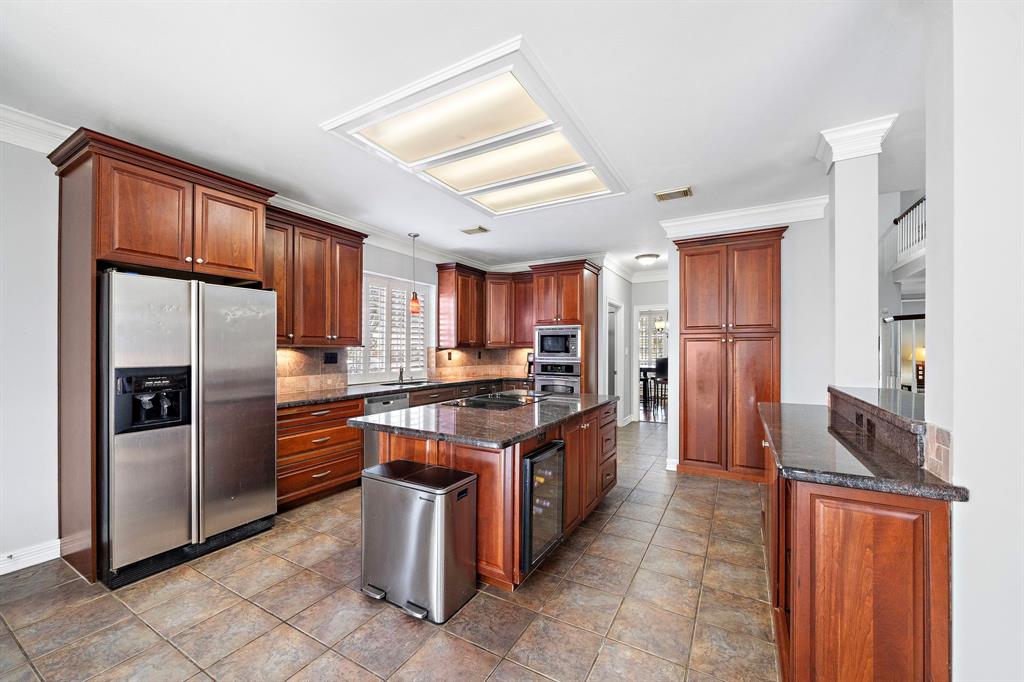 The gourmet kitchen is at the heart of the home fitted with granite countertops, stainless steel appliances, a raised breakfast bar, and an expansive island. Enjoy abundant storage options courtesy of the wooden cabinetry.