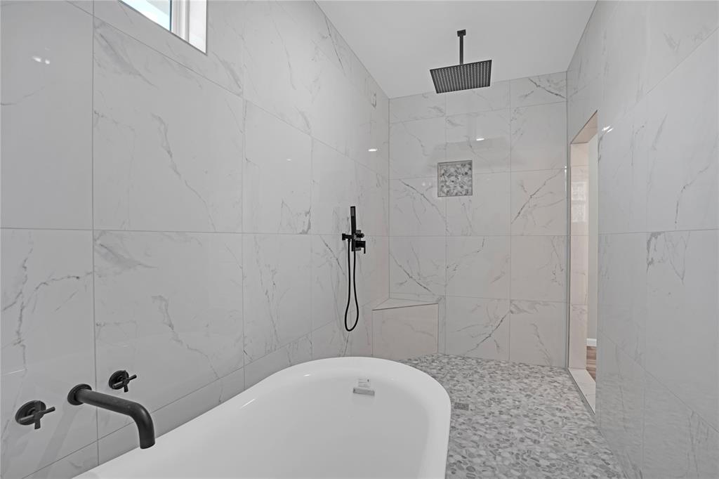 Soaking tub in huge walk-in shower area with bench