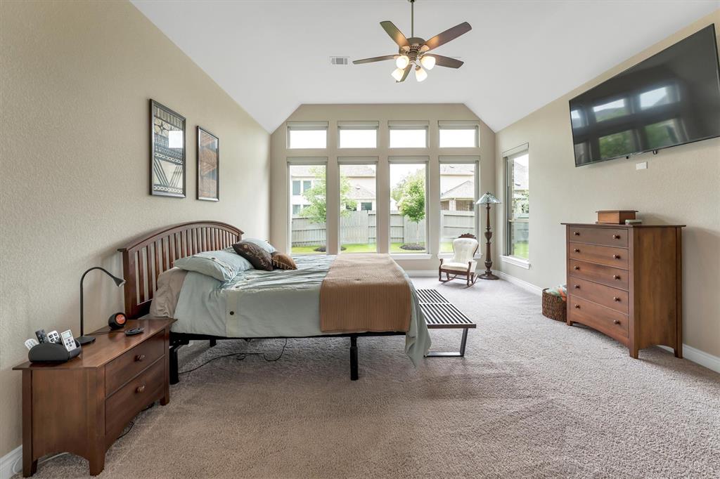 Primary bedroom illuminated by tall beautiful windows