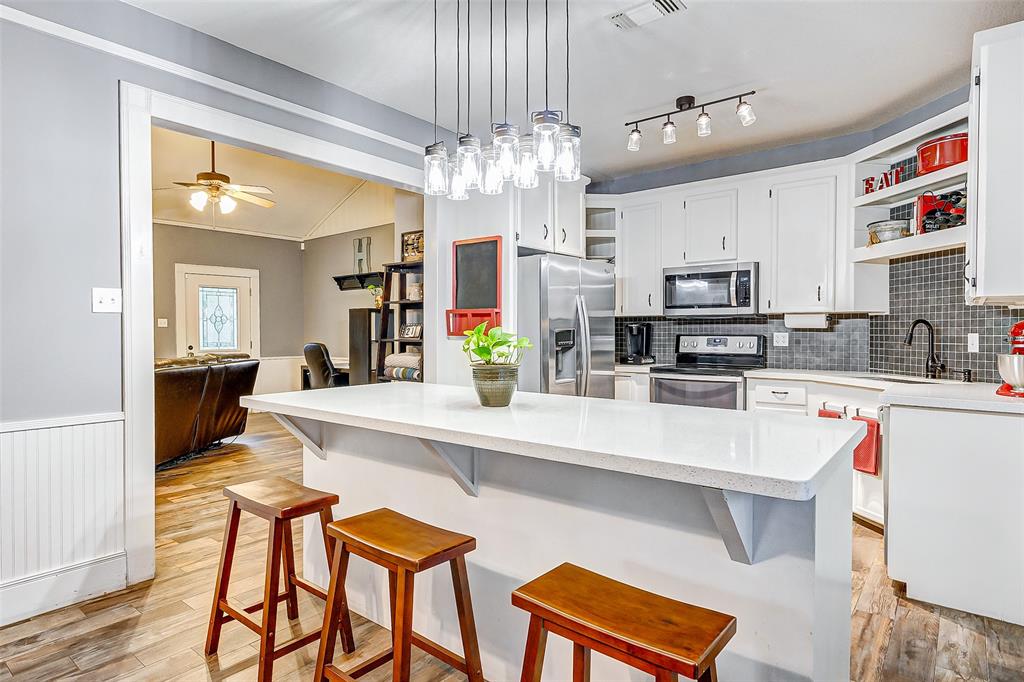 Step into culinary bliss in this stylish kitchen, boasting all-white cabinets, quartz countertops, and elegant pendant lighting illuminating the sleek island.