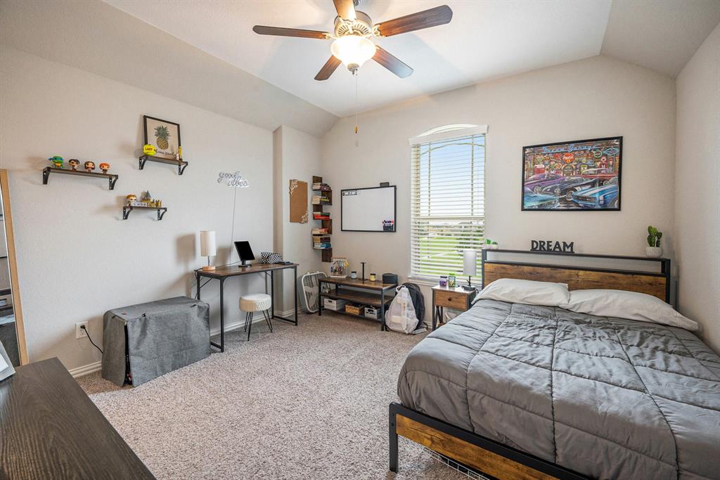 A tidy bedroom with a bed, desk, decorative shelves, and a \