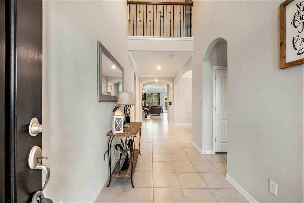 A well-lit interior hallway in a modern home with decorative elements, arched doorways, and a view into adjacent rooms.