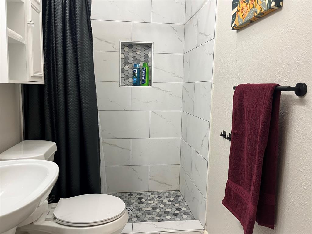 Renovated bathroom with tile in the walk-in shower, new toilet, new bathroom flooring and vanity.