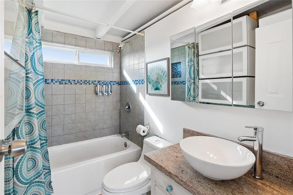 BATHROOM OFFERS A VESSEL SINK, AMPLE CABINETS FOR STORAGE AND A SHOWER & TUB COMBO.