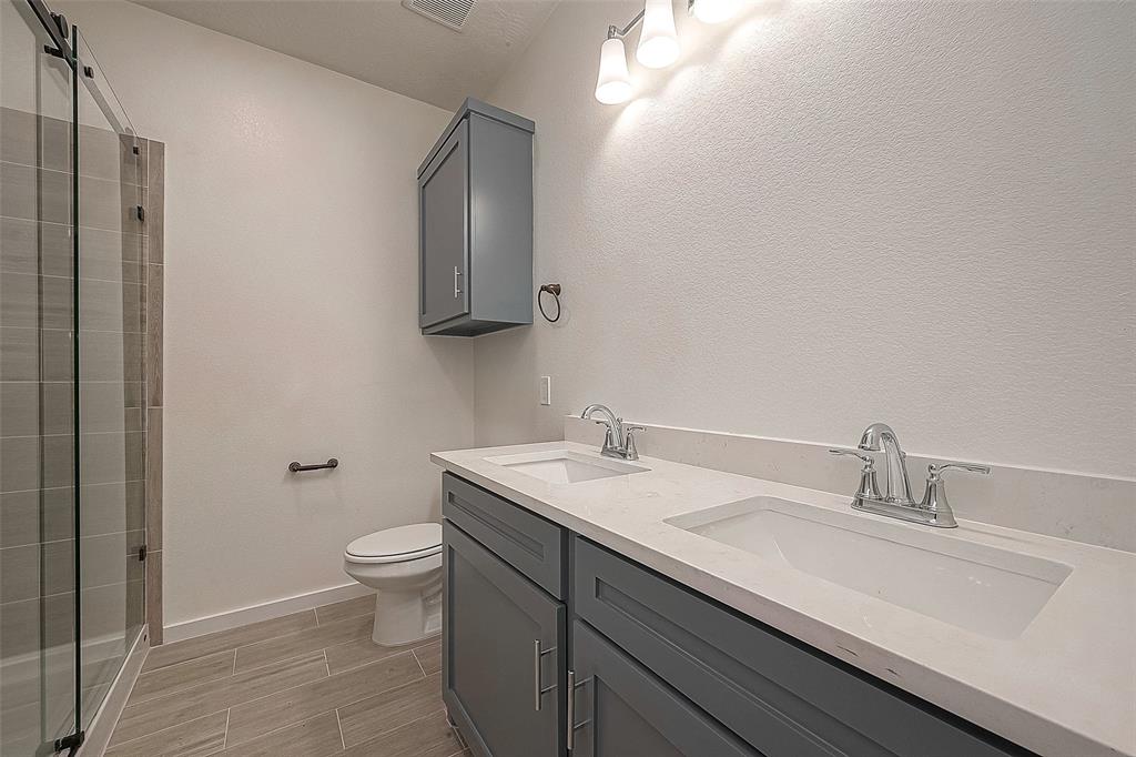 Primary bathroom with a beautifully designed shower, double sinks, sleek grey cabinets and tiled flooring. It has been carefully designed to provide both functionality and aesthetics.