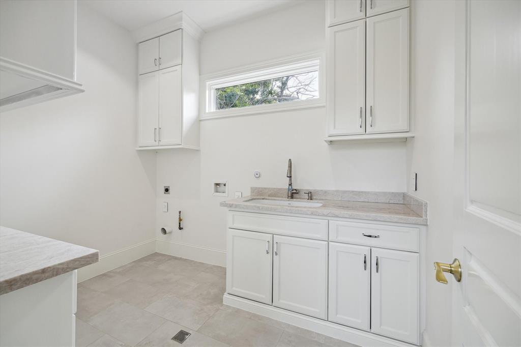 An oversize utility room found upstairs with counter space for folding, storage cabinets and utilitarian sink. A room that is sure to be appreciated.