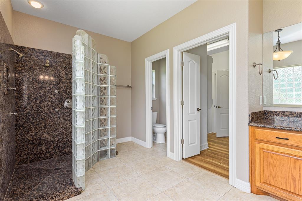 A closer view reflect the size of the large granite and glass block walk through shower with dual shower and massaging heads.