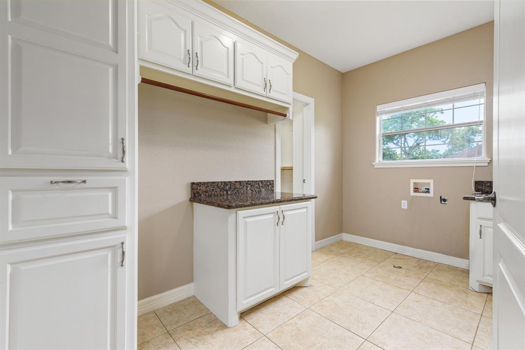 Oversized laundry room features a sink, folding space and abundant cabinets. Note the granite countertops which are featured throughout this beautiful home.