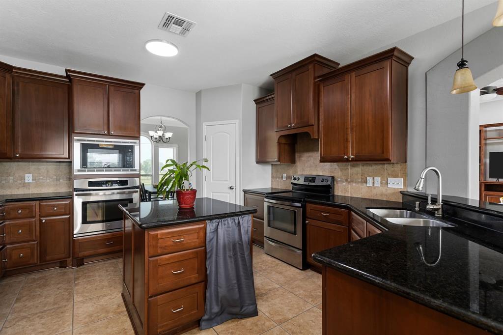 Stainless steel appliances.  Microwave, Electric Range, KitchenAid Dishwasher, Kenmore built-in Convection Oven & Kenmore Elite Refrigerator w/ tiled backsplash, cherry wood cabinets & black granite countertops.  Kitchen also features a center island.