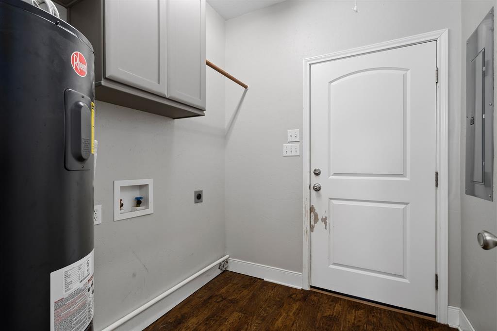 Utility room has wood like vinyl flooring, cabinets & clothes hanging bar.  Door leads to attached garage.