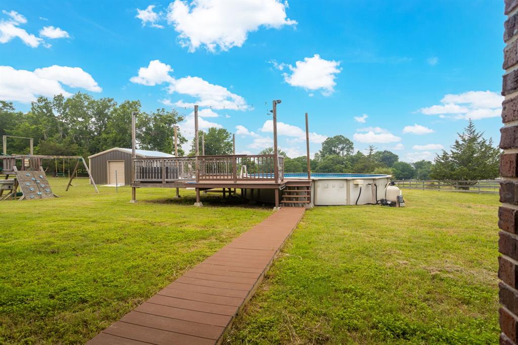 Above ground pool, wood deck, wooden playscape and 20x20 metal shop on slab.