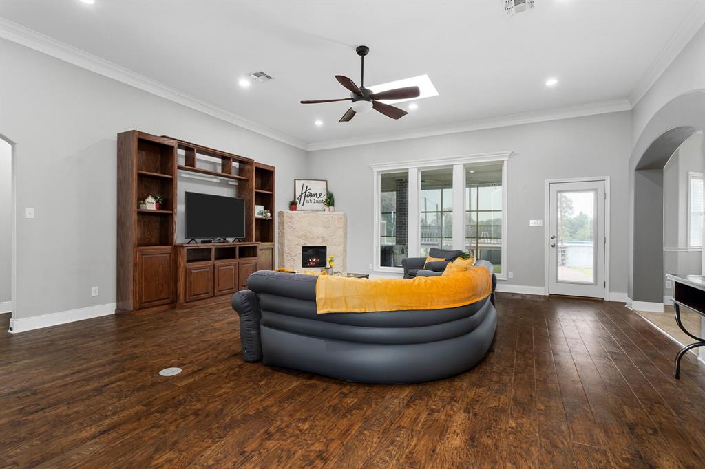 Wood like vinyl flooring, corner gas fireplace, crown molding and tall baseboard with ceiling fan and canned lights in Living room.