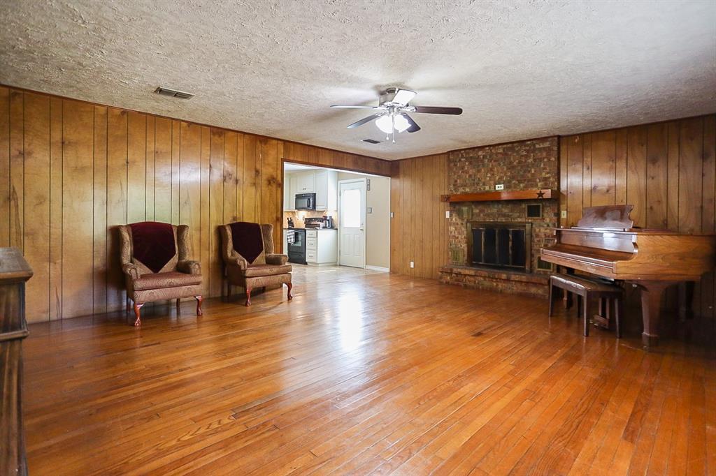 Large living room with outdoor view and hardwood floors.