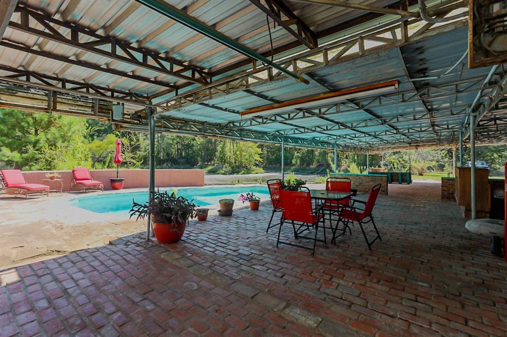 Covered brick patio with swimming pool.