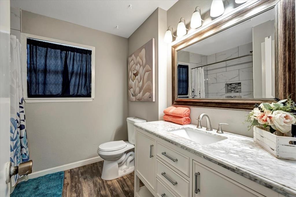 Renovated bathroom with massive vanity featuring a granite top.