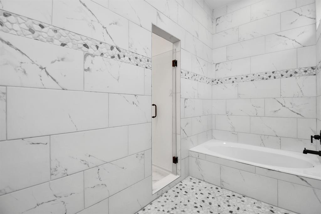 Tub is located within the shower area of the primary bath