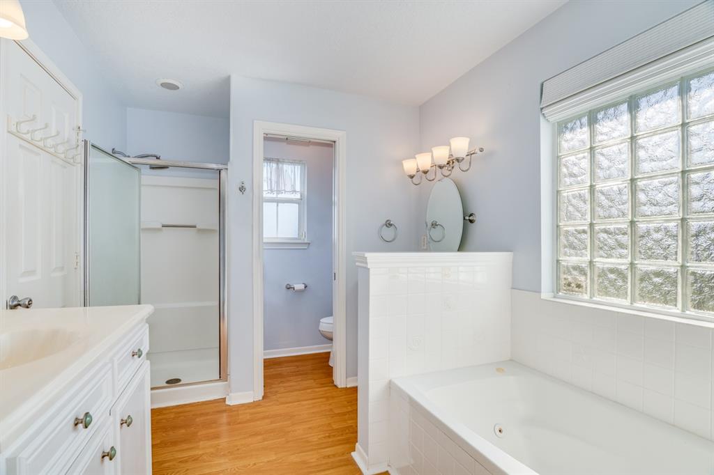 Separate shower, soaking tub, two vanities, and wood floors are the highlights of the primary bath.