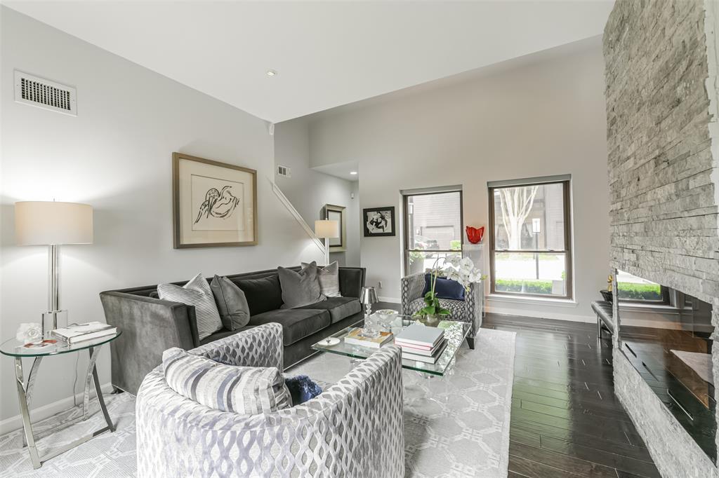 Another view of the living room highlights large windows, wall space for your art, pristine, recently installed engineered wood flooring, and a view of the manicured front yard.